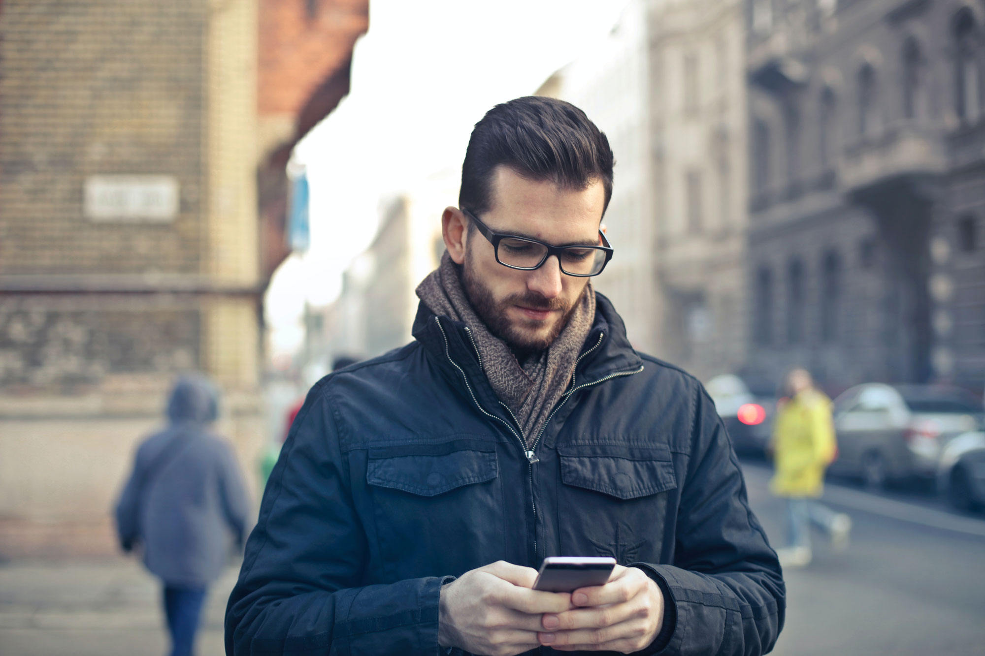 Man holding cell phone, walking outside